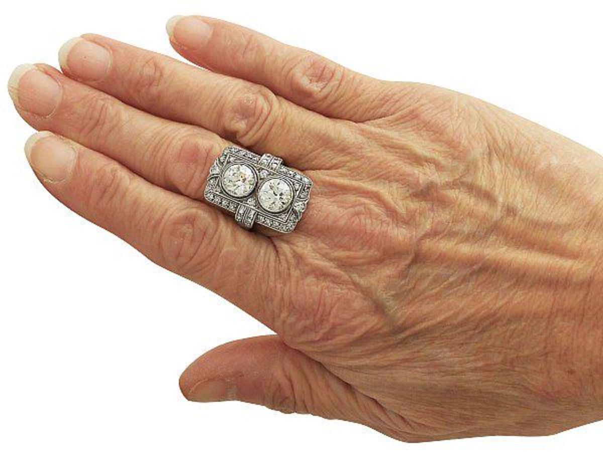 On-hand angled view highlighting the vertical two-stone layout and micro-pavé borders of a vintage lab diamond ring.