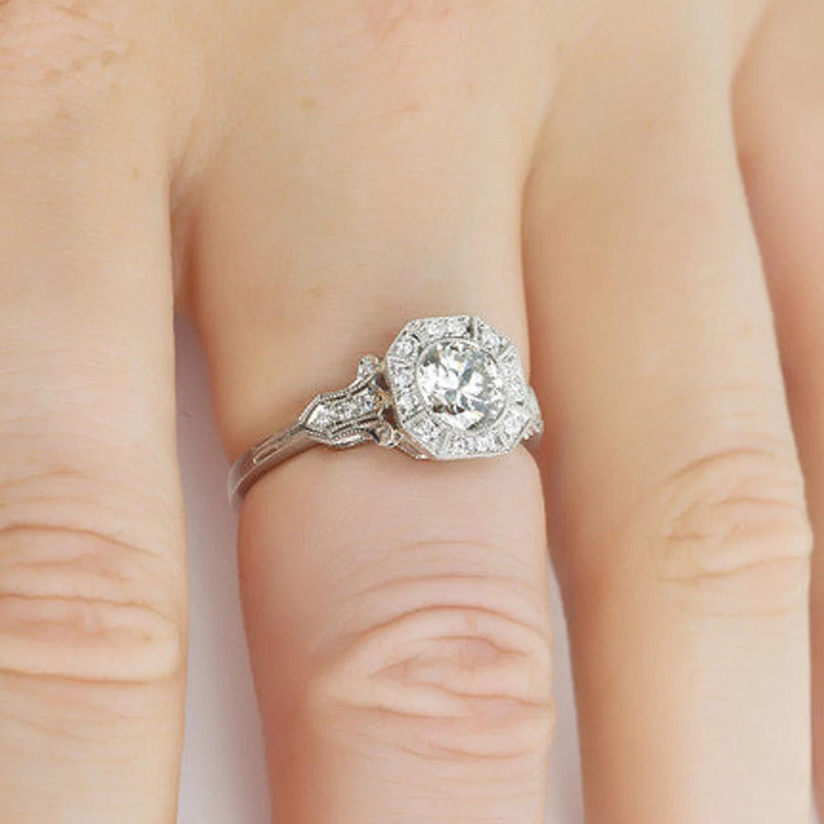 Side profile on finger showing raised center stone and vintage carved shoulder details.