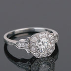 Studio shot on dark reflective surface showcasing geometric octagonal halo and round center lab diamond.