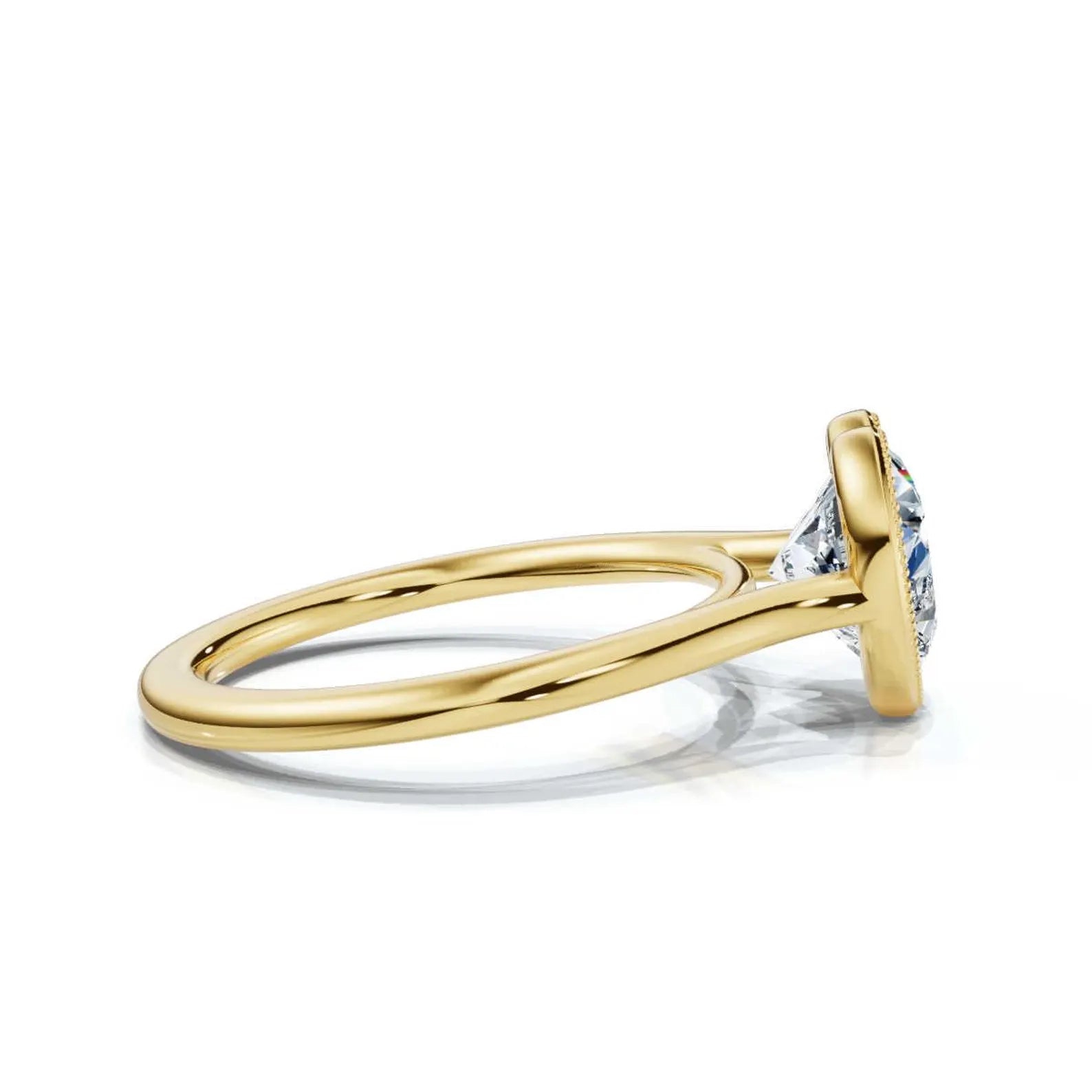 Side perspective view of a yellow gold heart cut diamond ring showing the smooth polished band tapering toward the bezel setting.