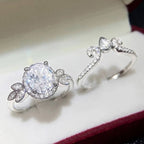 White ring box presentation displaying oval halo engagement ring alongside curved tiara wedding band.