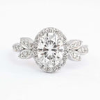 Isolated front view of 2 CT oval cut lab diamond halo engagement ring with leaf side accents on white background.