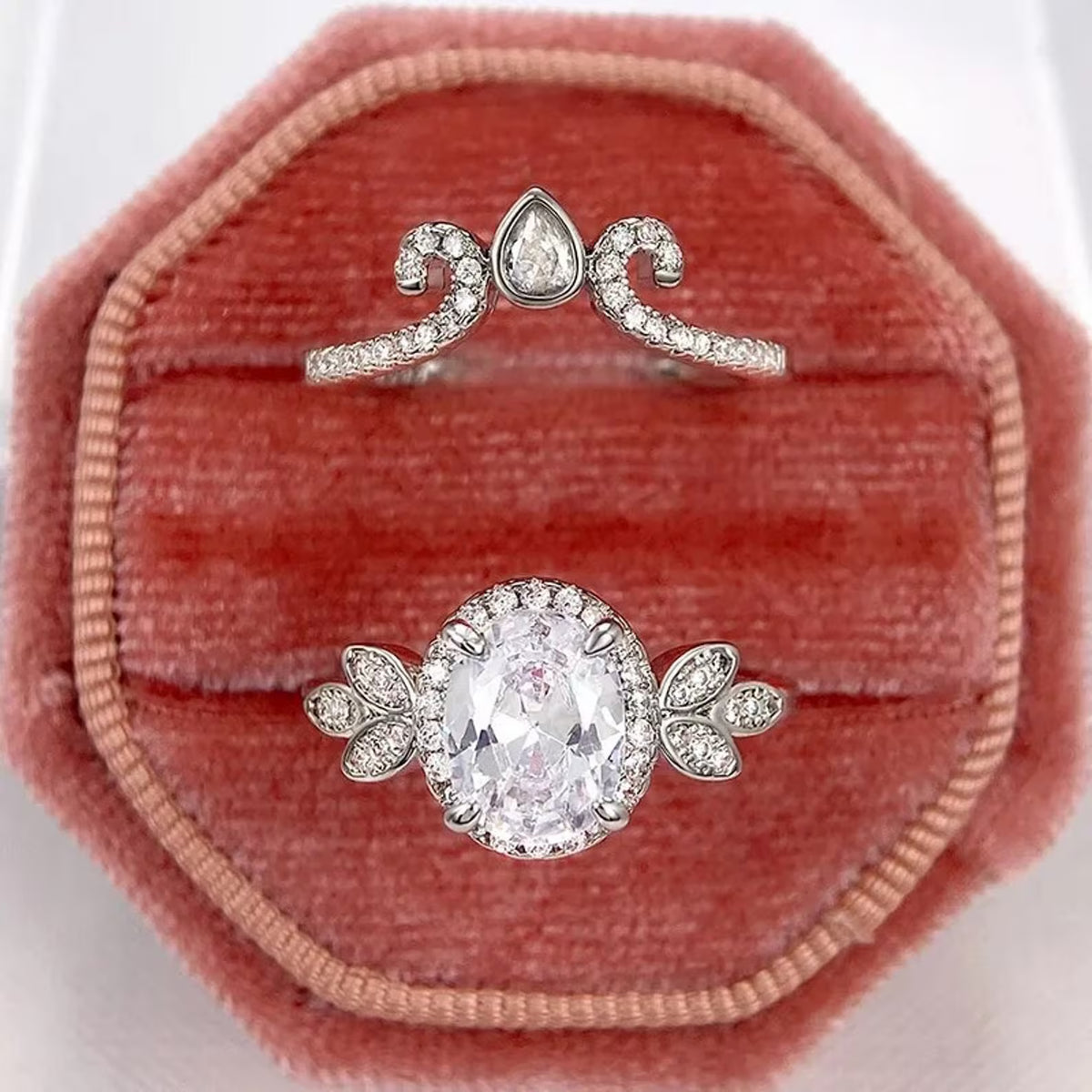 Overhead view in pink velvet octagon ring box displaying oval halo ring and tiara wedding band.
