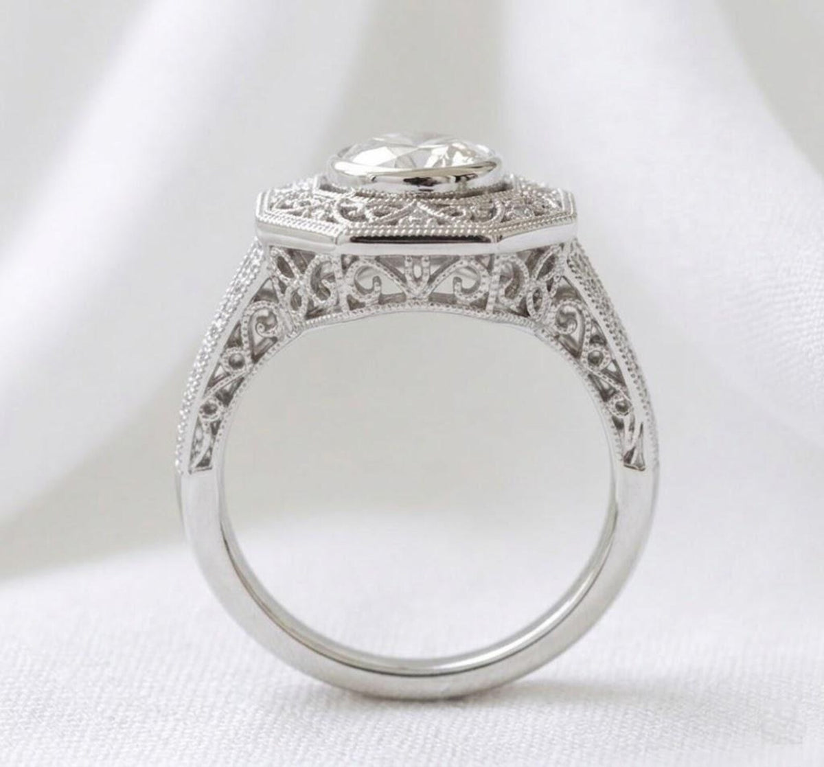 Direct side view of an Art Deco bezel set lab diamond ring highlighting the filigree arch bridge and smooth metal band.
