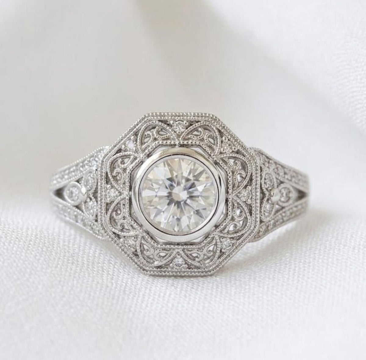 Top-down macro view of a 2 carat round lab diamond encased in an octagonal filigree halo with milgrain borders.