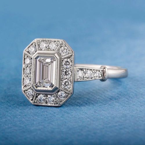 Close-up of a 2 CT emerald cut lab grown diamond showing hall-of-mirrors step cuts set in white gold with milgrain halo.