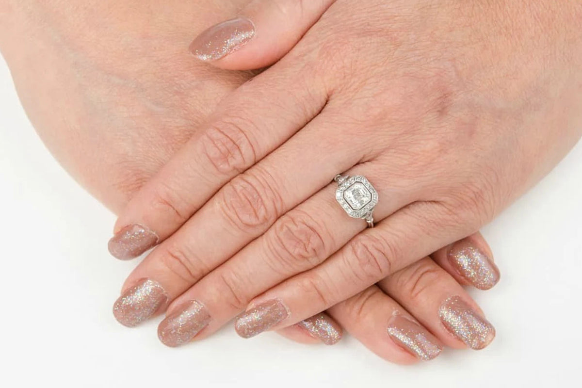 On-hand perspective displaying a 2 carat Asscher cut lab diamond vintage halo engagement ring in white gold.