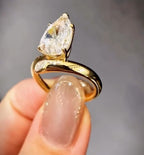 Side profile showing the elevated prong head and fluid gold bypass band of a 3 carat pear cut lab diamond ring.