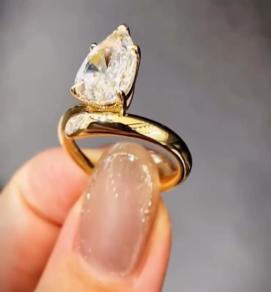 Side profile showing the elevated prong head and fluid gold bypass band of a 3 carat pear cut lab diamond ring.