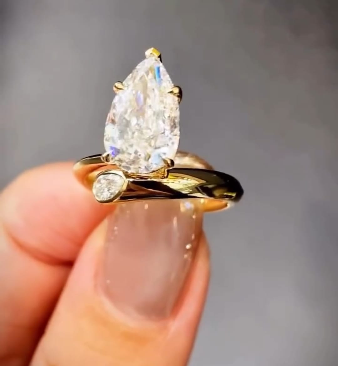 Detailed front view of a 3ct pear cut lab diamond ring showing the bezel-set pear accent stone on the band.