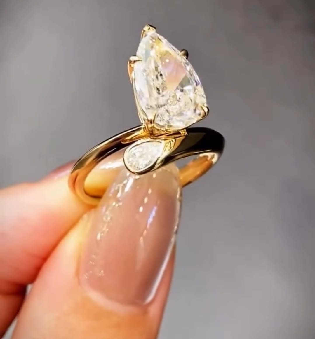 Three-quarter angle shot displaying the polished yellow gold curve and brilliance of a 3 Carat pear lab diamond ring.