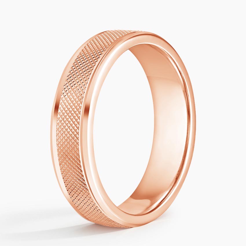 Angled view of rose gold men's wedding band featuring cross-hatch knurled texture and polished edges.