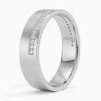Angled view of white gold men's wedding band with an off-center row of channel-set diamonds.