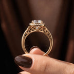 Side profile showing intricate vintage filigree scrollwork and hidden accent diamond beneath the cushion halo ring.