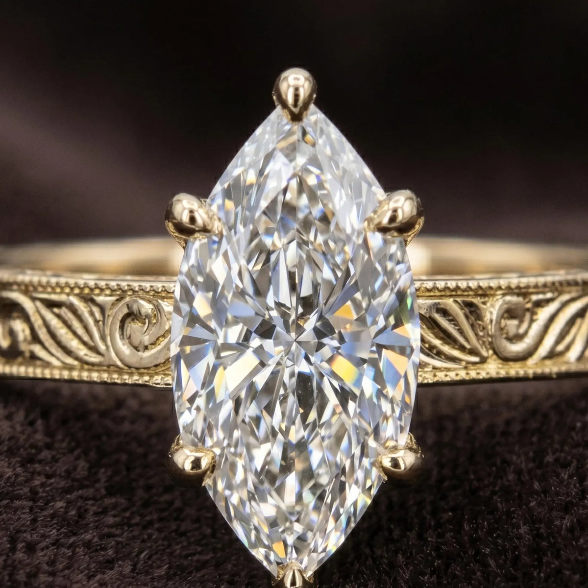 Ultra macro detail image of 3 CT marquise cut diamond facets and hand-carved floral pattern band with milgrain trim.