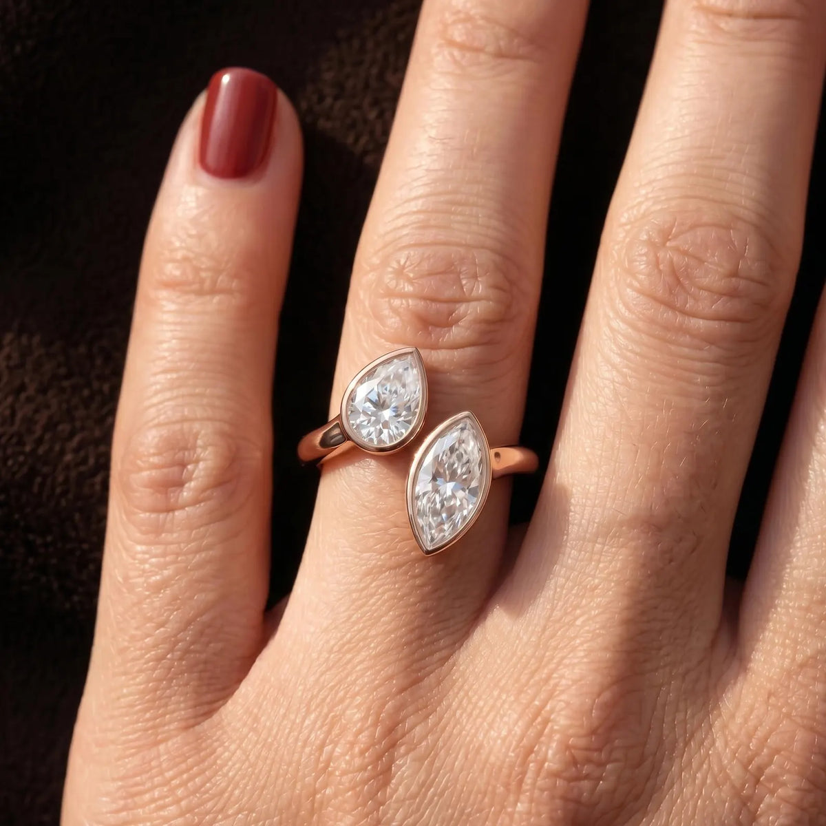 Top down view of two stone pear and marquise lab grown diamond ring on finger.