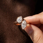 Close up shot of pear cut and marquise cut lab grown diamonds held in fingers.