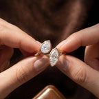 Hands holding an open cuff Toi et Moi lab grown diamond bezel ring.
