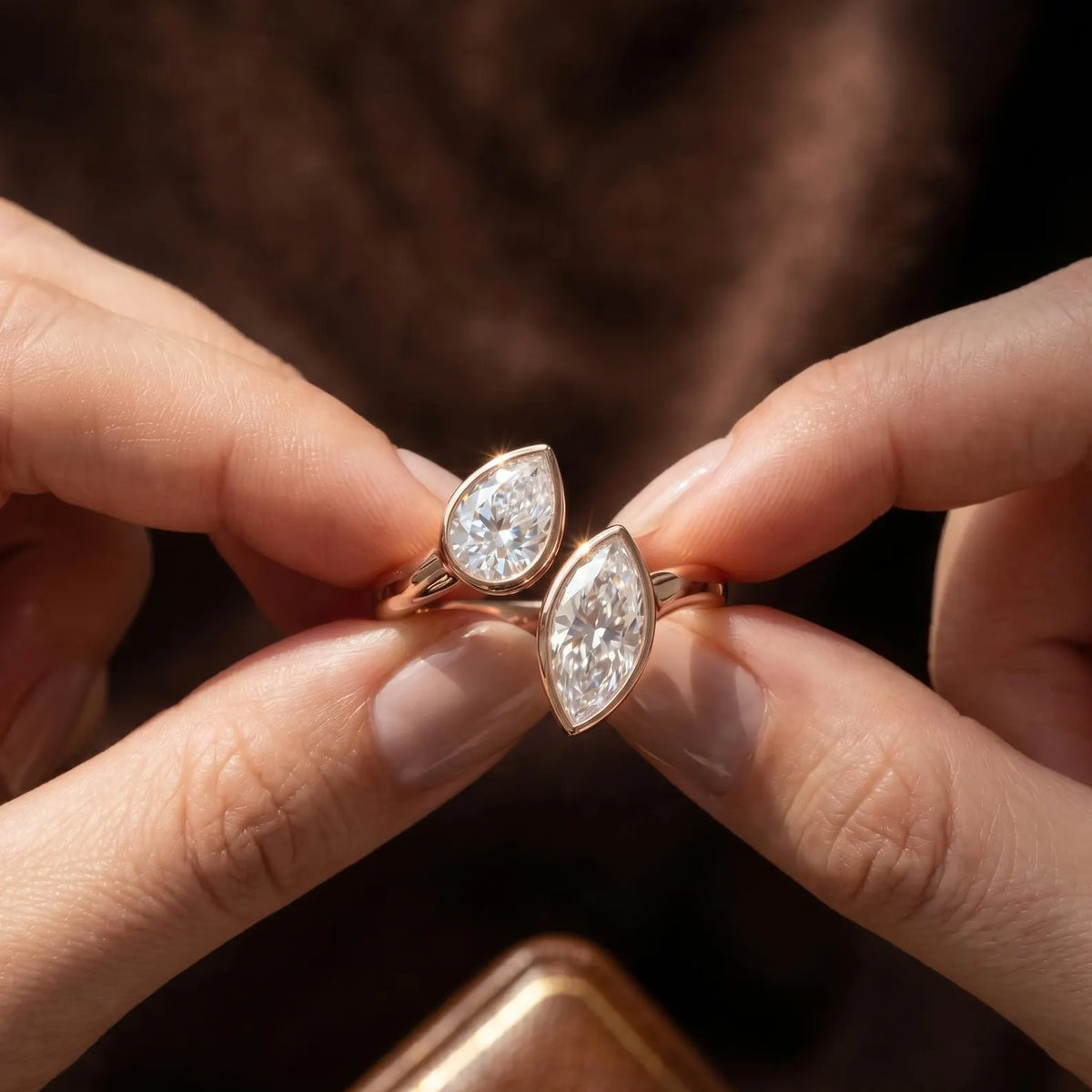 Hands holding an open cuff Toi et Moi lab grown diamond bezel ring.