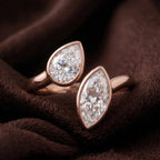Macro photo of rose gold pear and marquise lab diamond ring on brown velvet.