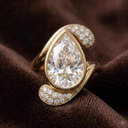 Close up shot of 3 carat pear cut lab grown diamond ring resting on brown velvet.
