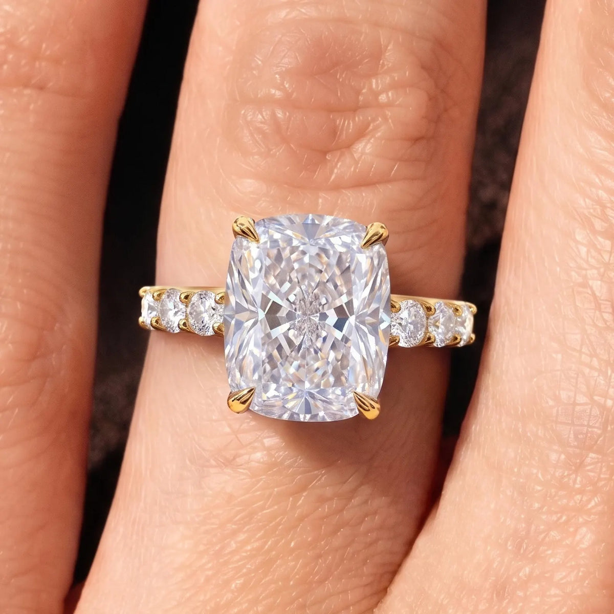 Top view of 4 carat elongated cushion lab diamond ring with accent band on finger.