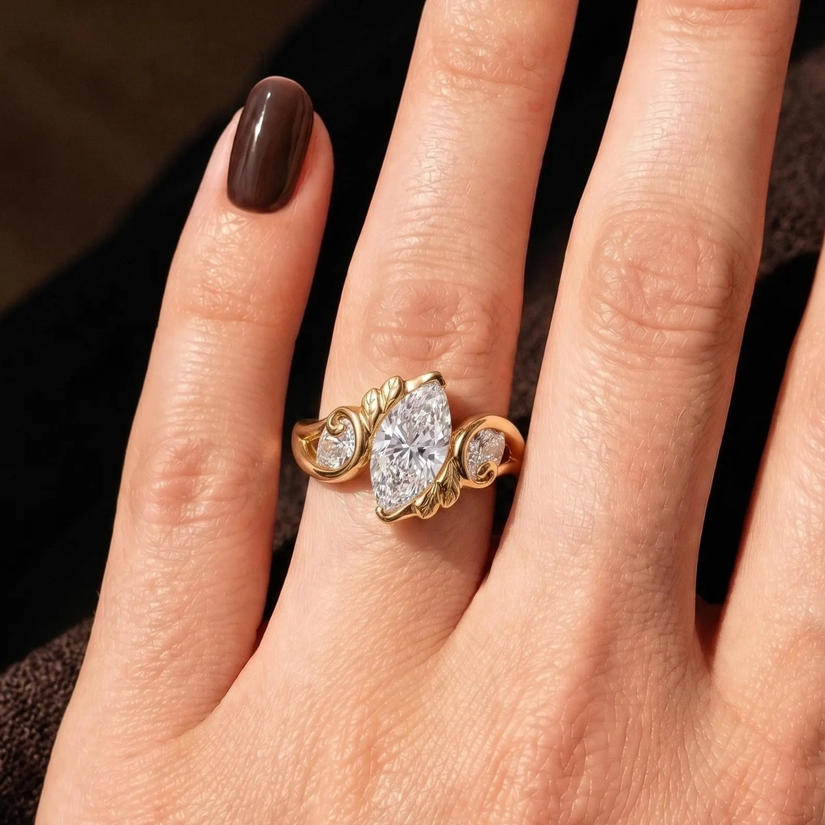 Top-down front view of a 2 CT marquise cut lab grown diamond botanical engagement ring worn on a finger.