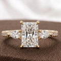 Frontal macro shot of a 3 CT radiant cut lab grown diamond engagement ring with pear side stones in 14K yellow gold.