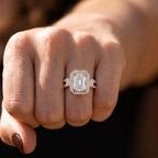 Wearer showing off a 3 carat emerald cut lab diamond ring on finger under soft lighting.