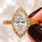 Close-up top view of a 3 CT marquise lab grown diamond engagement ring with scalloped halo and yellow gold filigree scrollwork band.