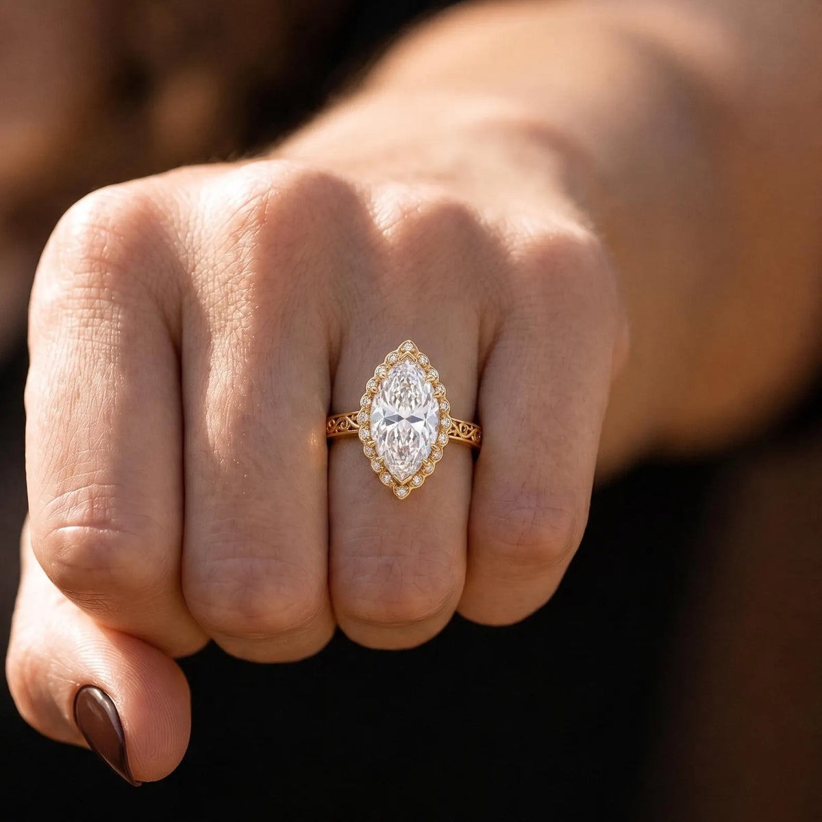 Woman wearing 3 CT marquise lab diamond vintage filigree ring shown in natural light on finger.