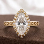 Flat lay photo of a 3.0 CT marquise cut lab diamond vintage halo ring with engraved shank on brown fabric background.