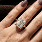 Close-up top view of a 4 CT step cut emerald lab diamond ring in 14k yellow gold with split shoulder claw prongs.