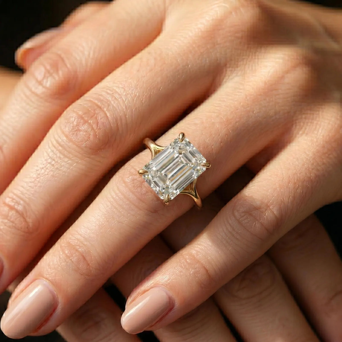 Perspective view of a large 4ct emerald cut lab-created diamond solitaire ring on hand.