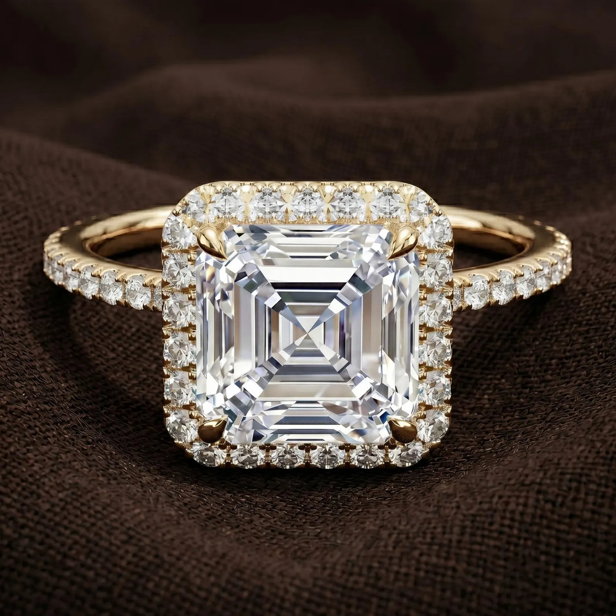Detailed macro photo of a 3 CT Asscher cut lab diamond displaying concentric step-cut facets and pave halo on brown fabric background.