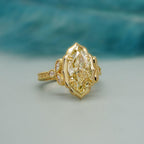 Perspective angle view of a 4 carat fancy yellow marquise cut lab grown diamond engagement ring in yellow gold.