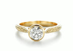 Front view of a 2 CT round lab grown diamond bezel set engagement ring in hand-engraved 18K yellow gold.