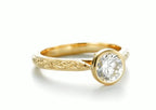 Angled perspective showing 2 carat round brilliant lab diamond in a secure bezel setting with engraved band.