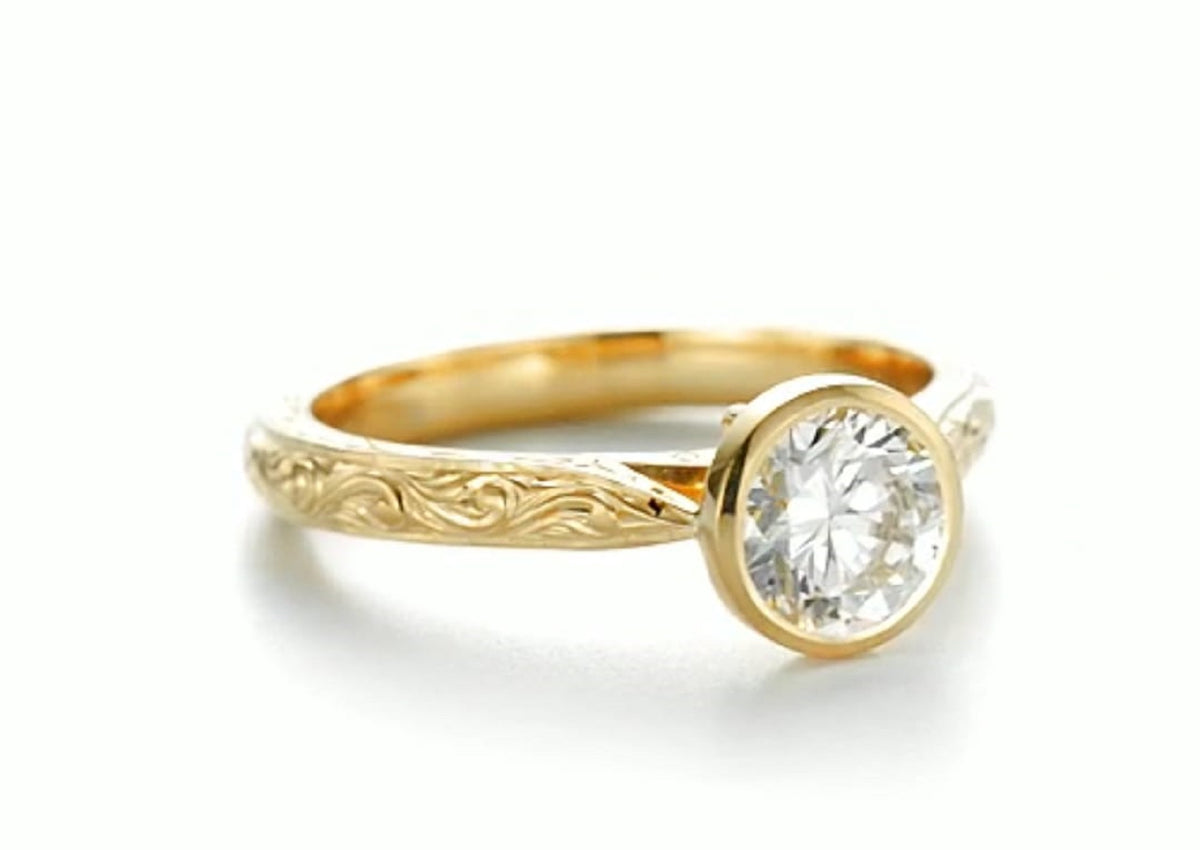 Angled perspective showing 2 carat round brilliant lab diamond in a secure bezel setting with engraved band.