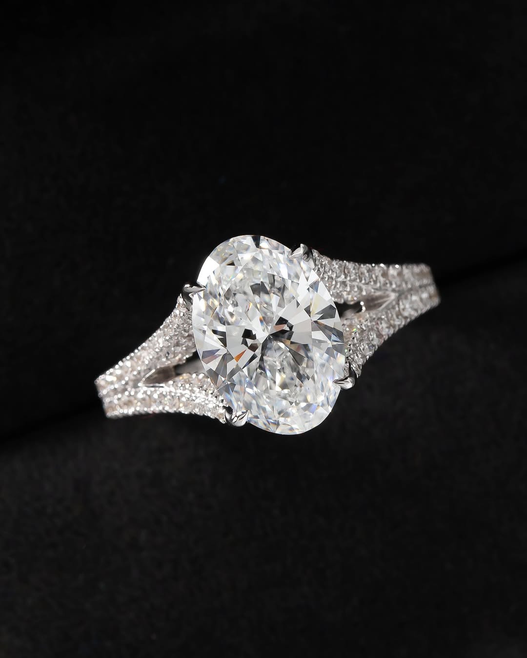 Direct top view of a 3 carat oval lab diamond showcasing brilliant facets and split pavé diamond shoulders.
