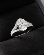 Angled view of 3 CT oval cut diamond ring with sparkling split-shank diamond accents displayed in a black ring box.