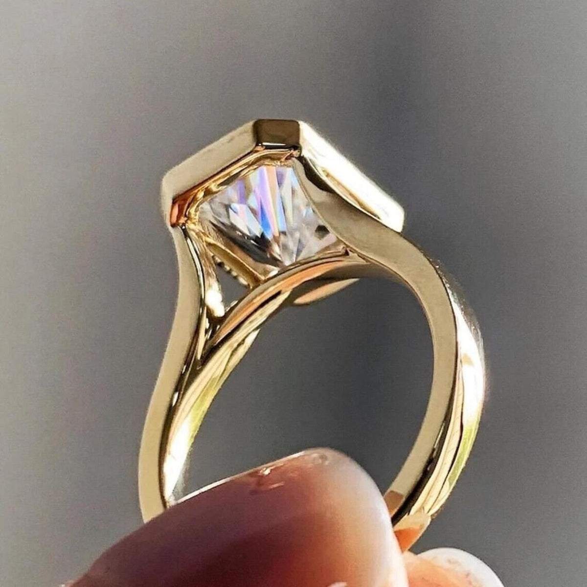Perspective side view of yellow gold bezel engagement ring featuring a 4 carat radiant cut lab diamond.