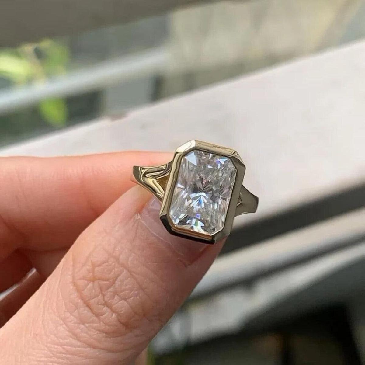 Front close-up view of radiant cut lab diamond framed by a smooth yellow gold bezel border.