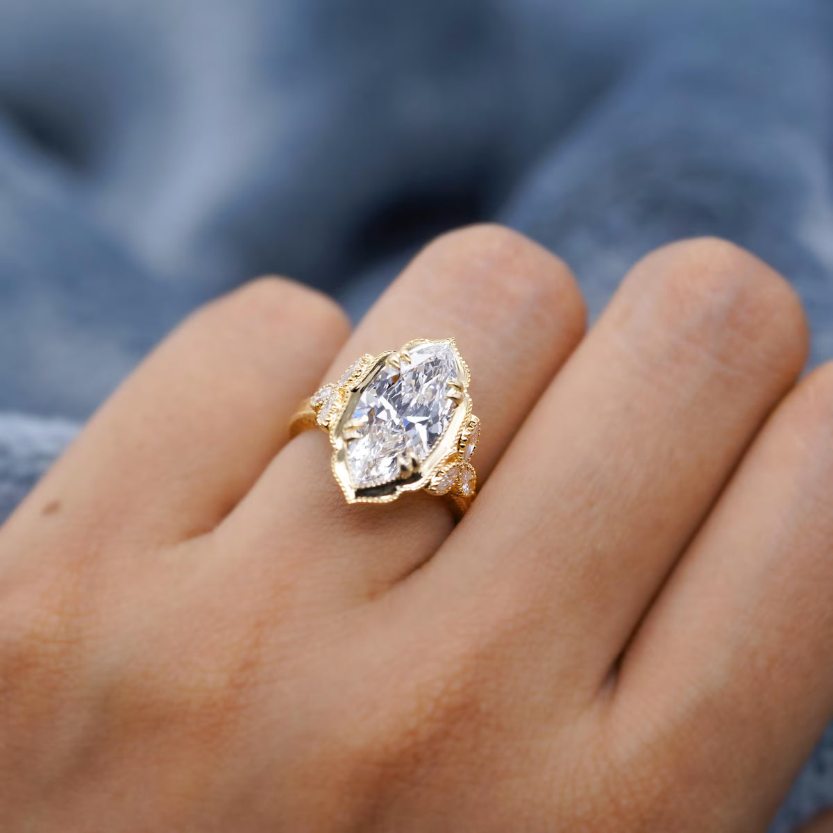 Close-up top angle shot of a 4 carat marquise cut lab-grown diamond ring worn on finger.