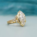 Angled macro studio shot highlighting claw prongs and marquise cluster accents on yellow gold band.