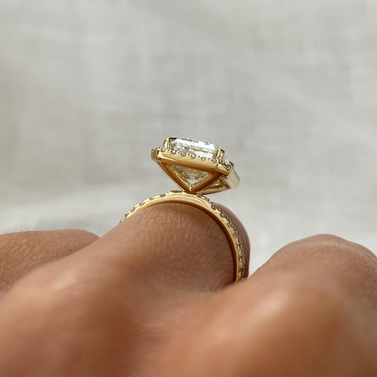 Elevated side profile view of a 4 carat emerald cut halo engagement ring in solid yellow gold.