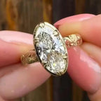 Top view of a large 4 CT oval cut lab grown diamond solitaire ring with milgrain trim and engraved yellow gold band.