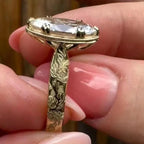 Elevated close-up of a 4 carat oval lab created diamond ring featuring milgrain detailing and engraved rose pattern.