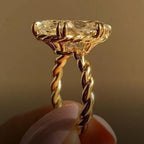 Close-up side perspective of yellow gold twisted rope engagement ring with double claw prongs.