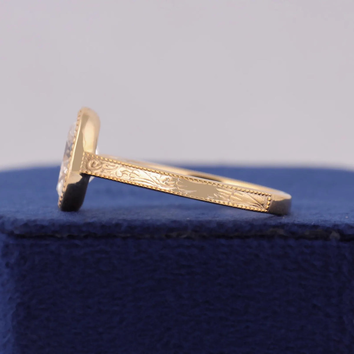 Close-up side profile displaying intricate hand-engraved scroll pattern and milgrain border on gold band.